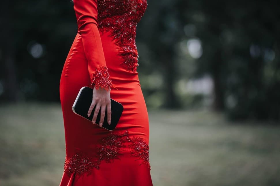 a woman wearing a red tight dress and holding a purse