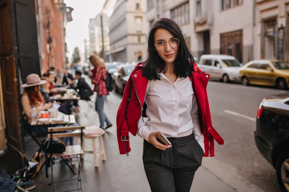 a young woman in formal attire and glasses walking down the street