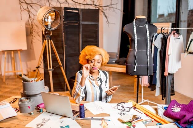 A girl with a phone in her hands sits in her studio